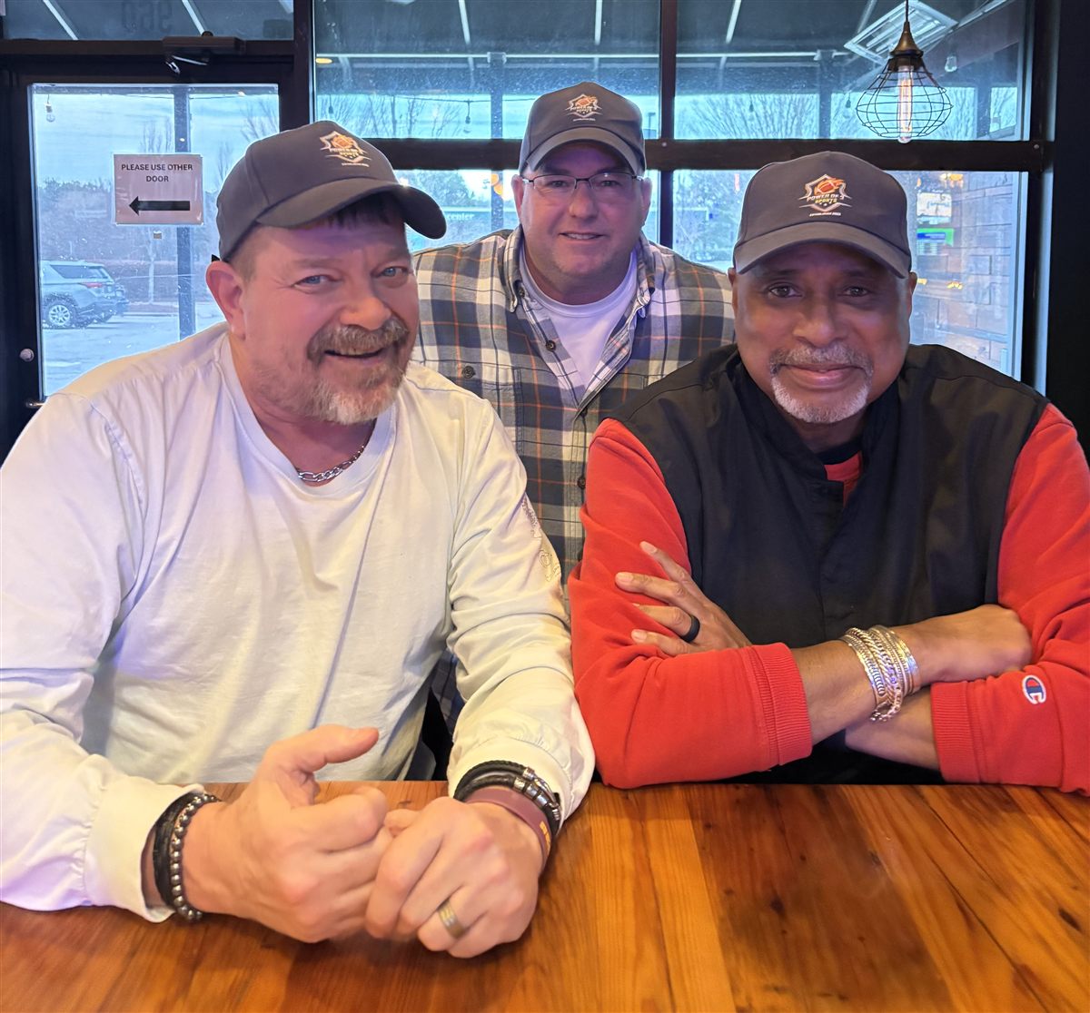 The three founders of Power of 3 Sports wearing Power of 3 caps